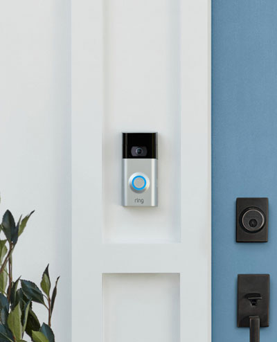A Ring video doorbell mounted on the wall, next to a blue door